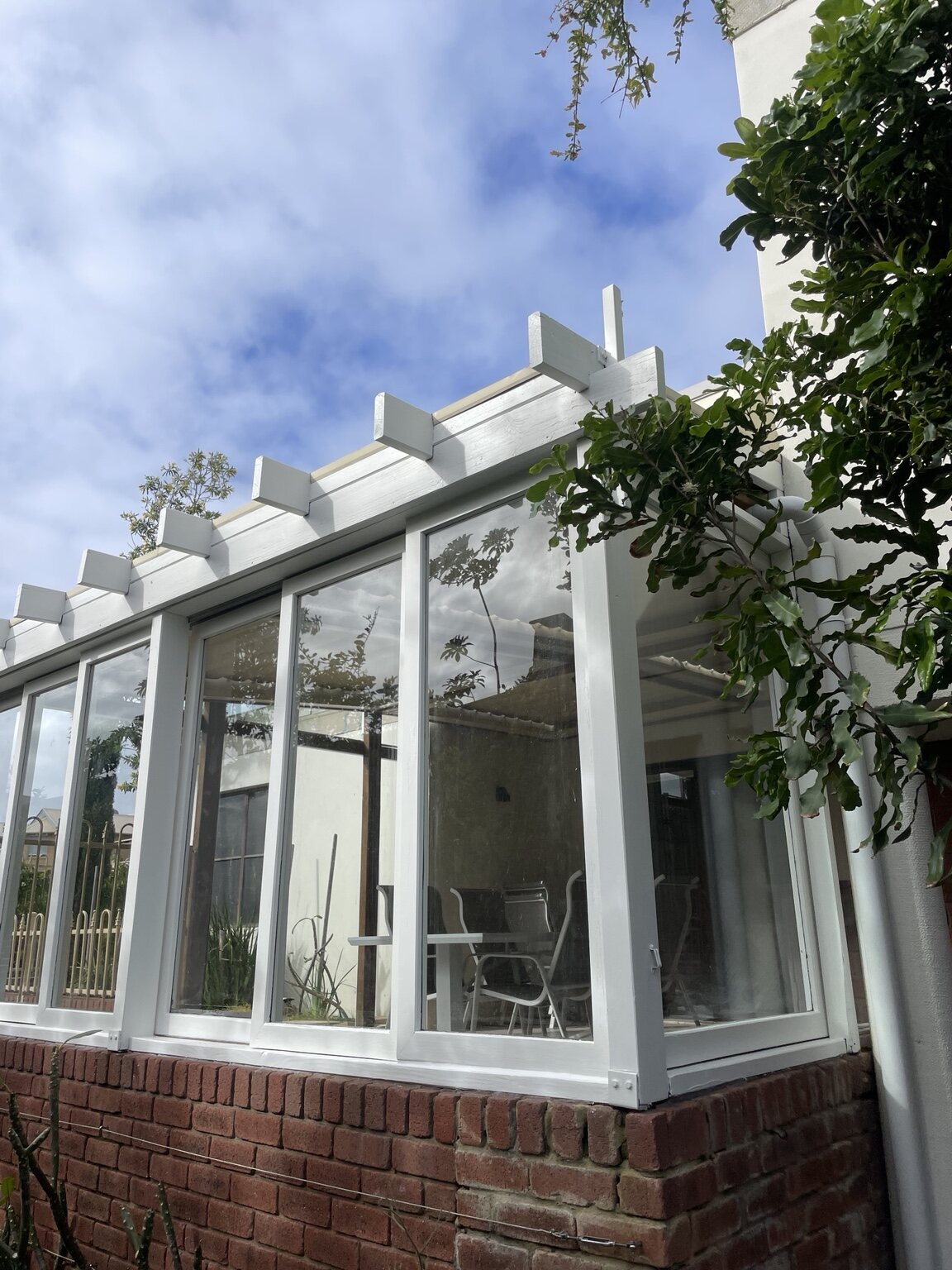 Freshly restored white exterior timber pergola and window frames